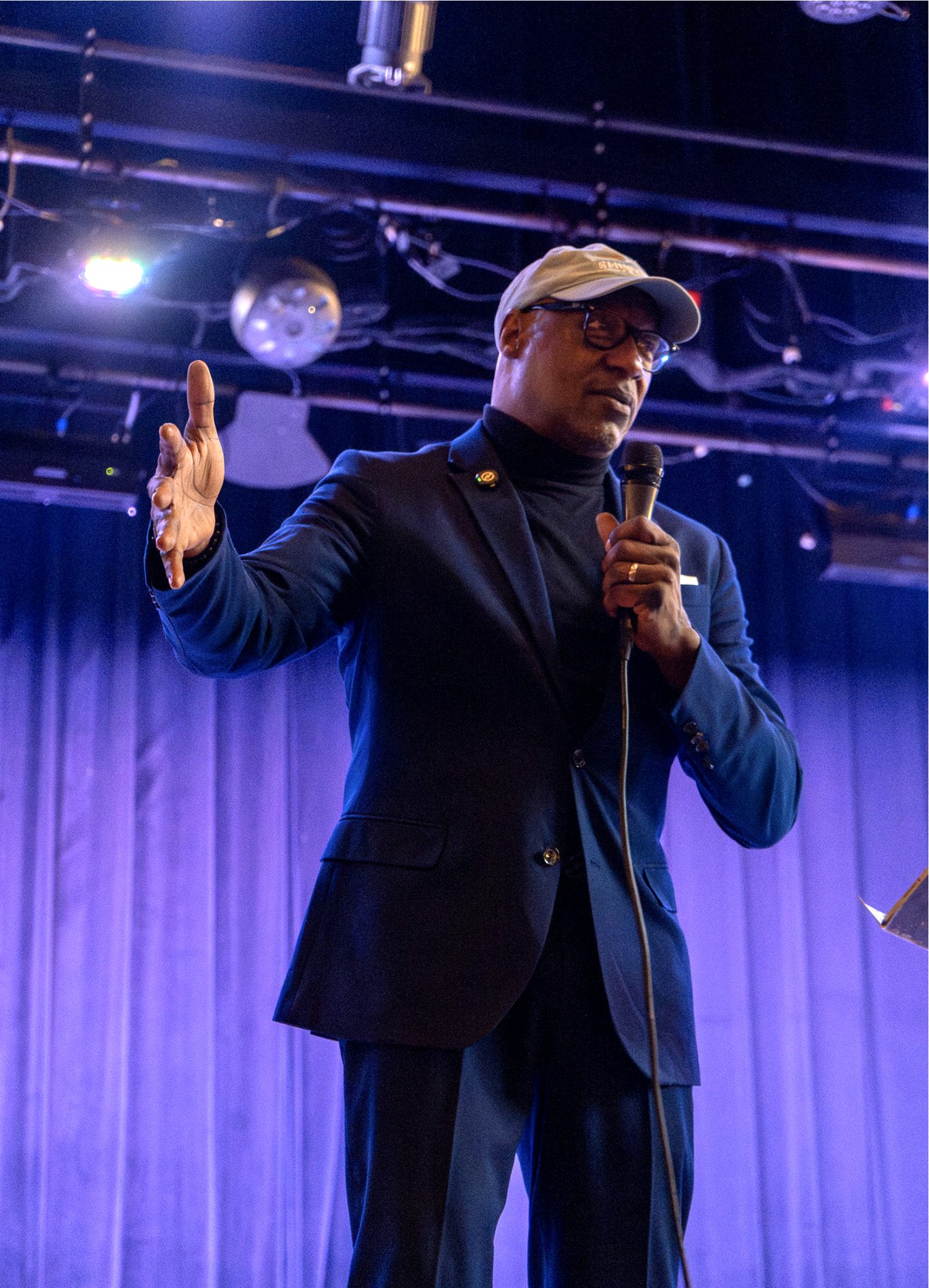 Bernard Bell speaking on stage with a microphone